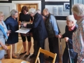 Job Schräder und Besucher schauen sich die Mappe mit Fotos zum Borgholzhausener Kartoffelmarkt an